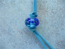 Transparant met blauw frit glaskraal aan suede ketting handg