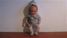 Baby popje met kleren en een muts uit de jaren 50.