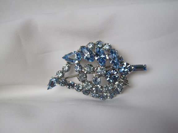 Broche zilverkleurig bloemtakje met twee tinten blauwe kristal rijnsteentjes 5.2x3.0 cm. - nr. 1