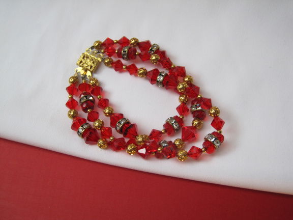 Armband goudkleurig drie strengen met rood kristal en spacers 18.5 cm - nr. 1