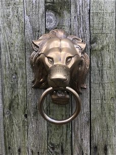 Een leeuwenkop, aluminium-messing kleur, als deurklopper