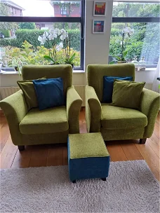 Groene fauteuils met bijpassend voetenbankje en kussens.