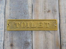 Bord met de tekst , TOILET messing, kado