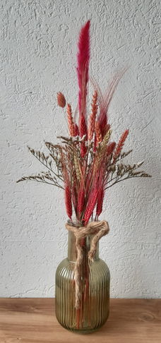 Groene glazen vaas met droogbloemen in de kleur fuchia.